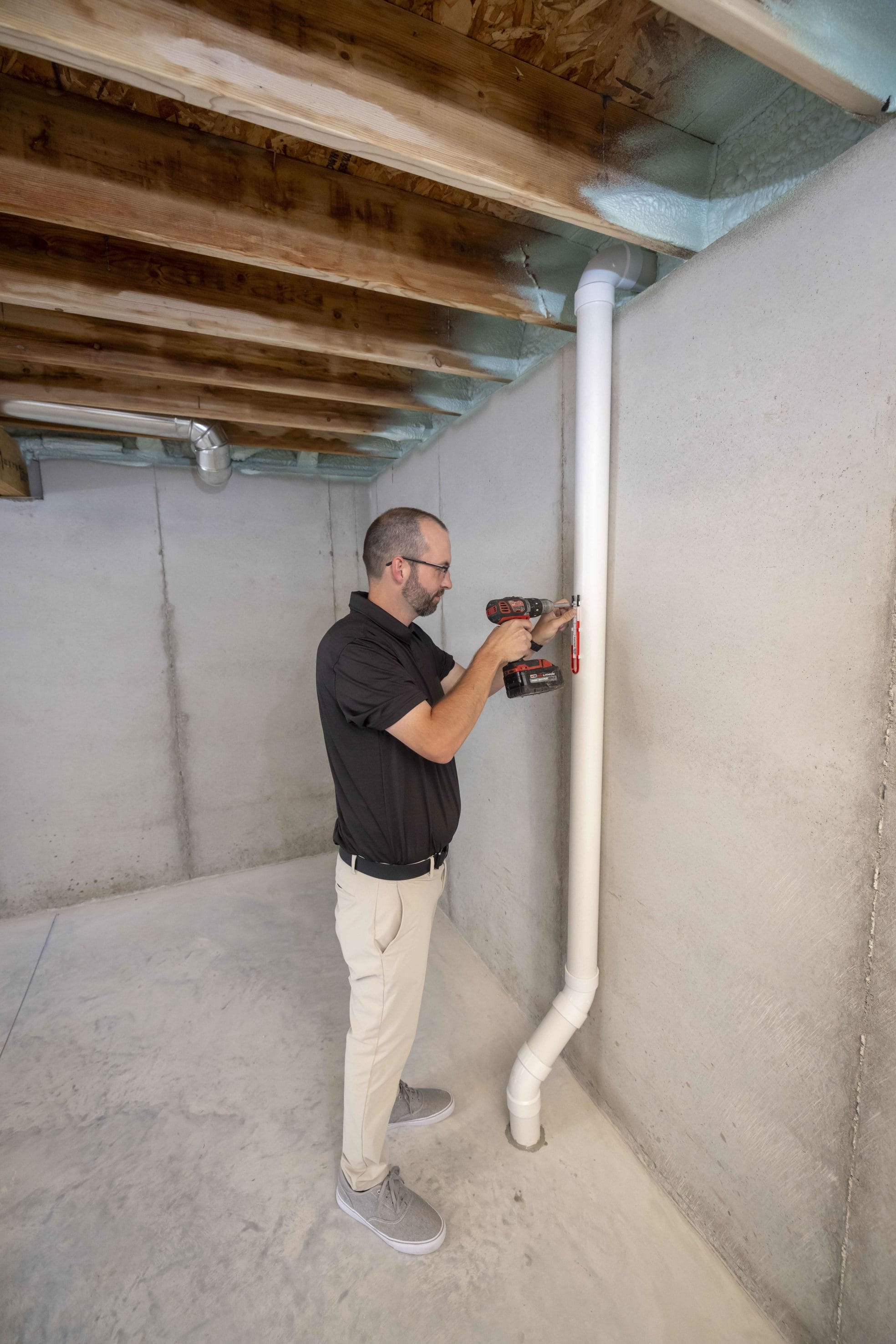 Technician Installing Commercial Radon Mitigation System in Basement
