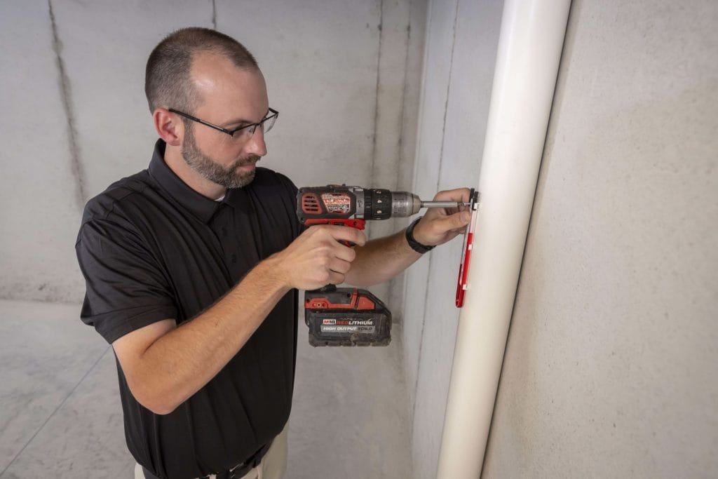 Technician Installing Commercial Radon Mitigation System in Arizona Basement
