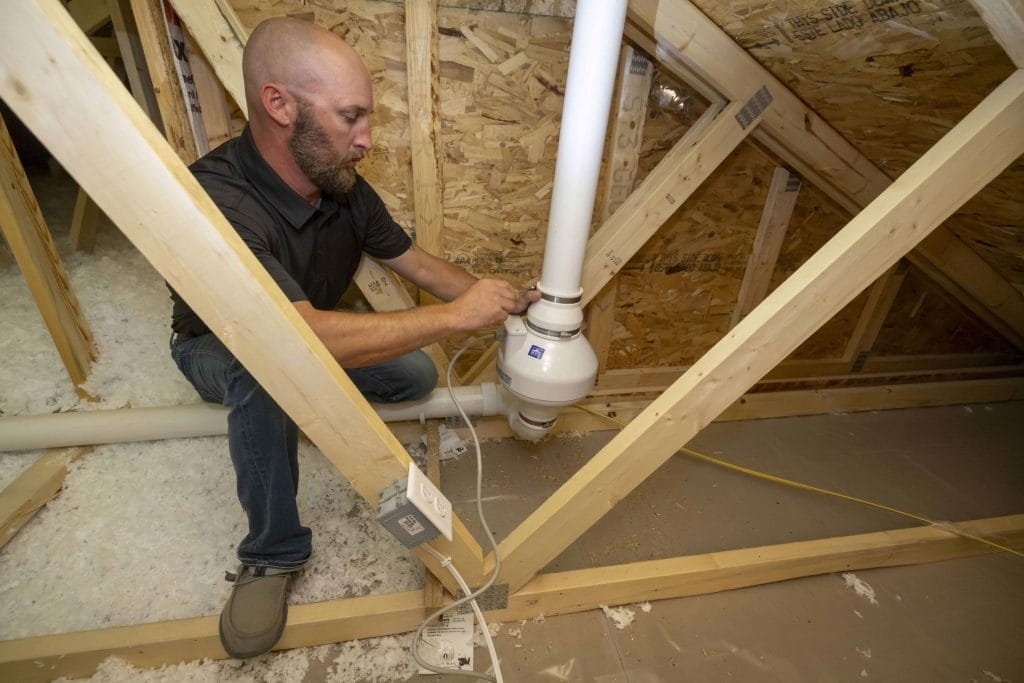 Man Installing Radon Mitigation System in Texas Attic