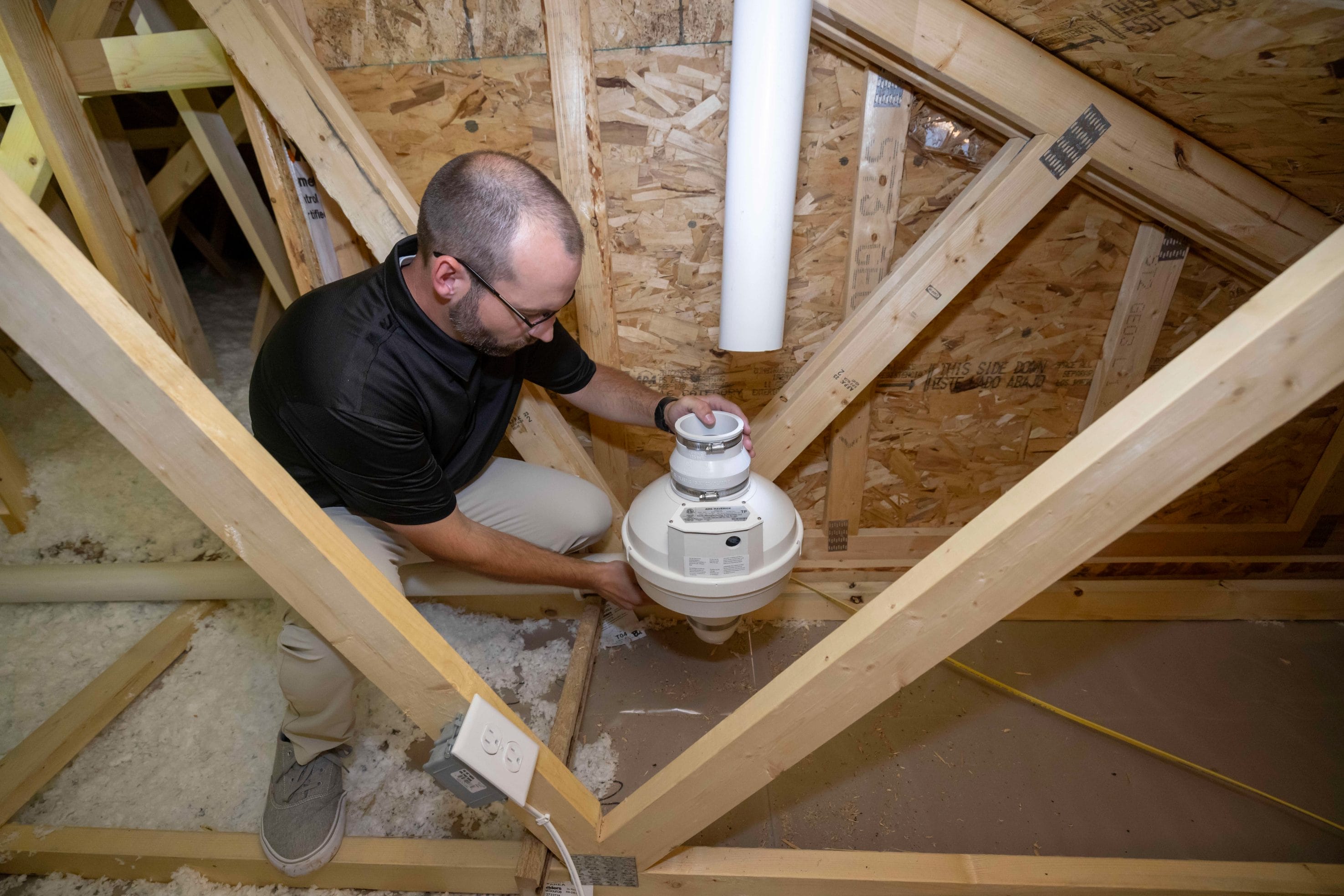 Technician Inspecting Radon System Repair in Attic
