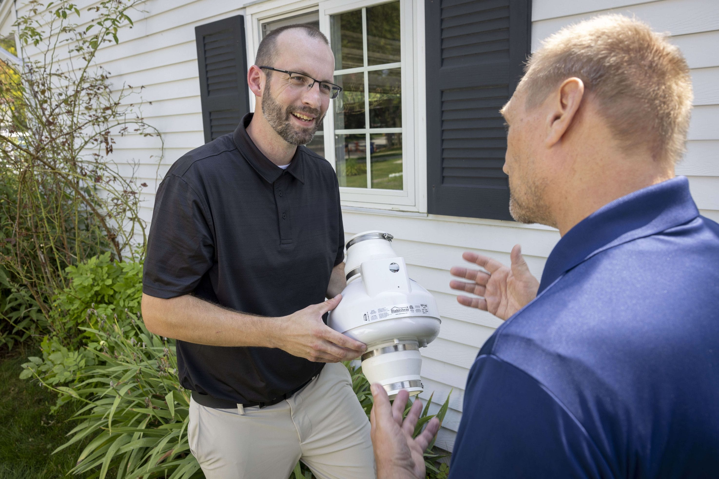 Radon mitigation expert discussing equipment installation
