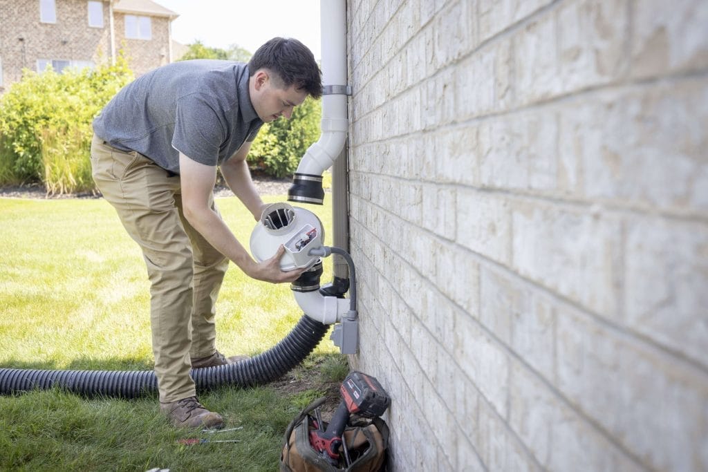 Technician Installing Radon Mitigation System in Texas Home
