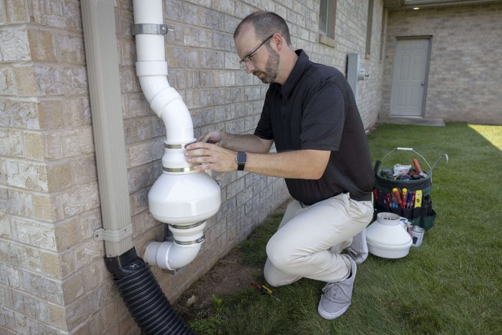 Technician Inspecting Radon Mitigation System in Arizona
